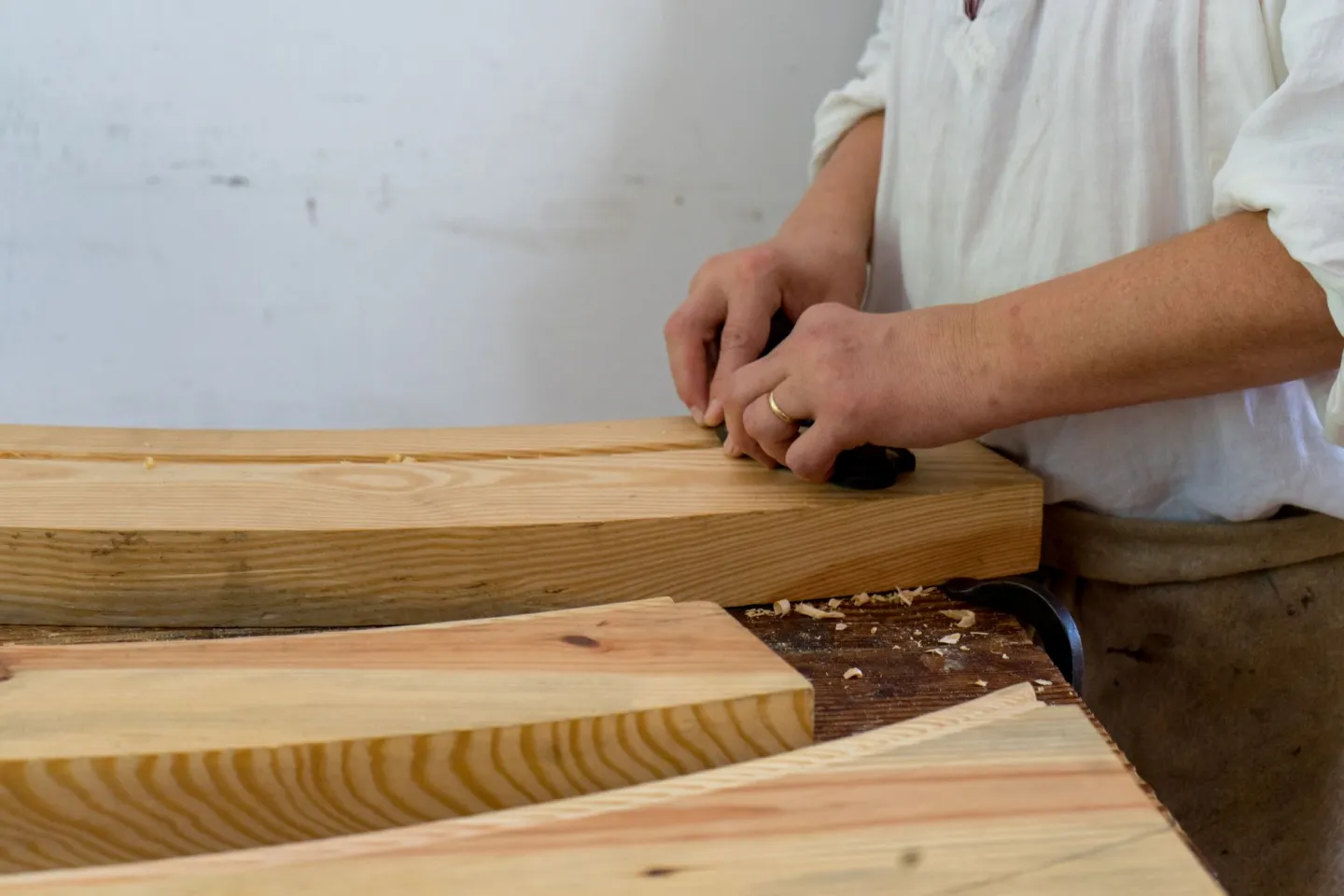 Menuisier façonnant des planches de bois dans son atelier.