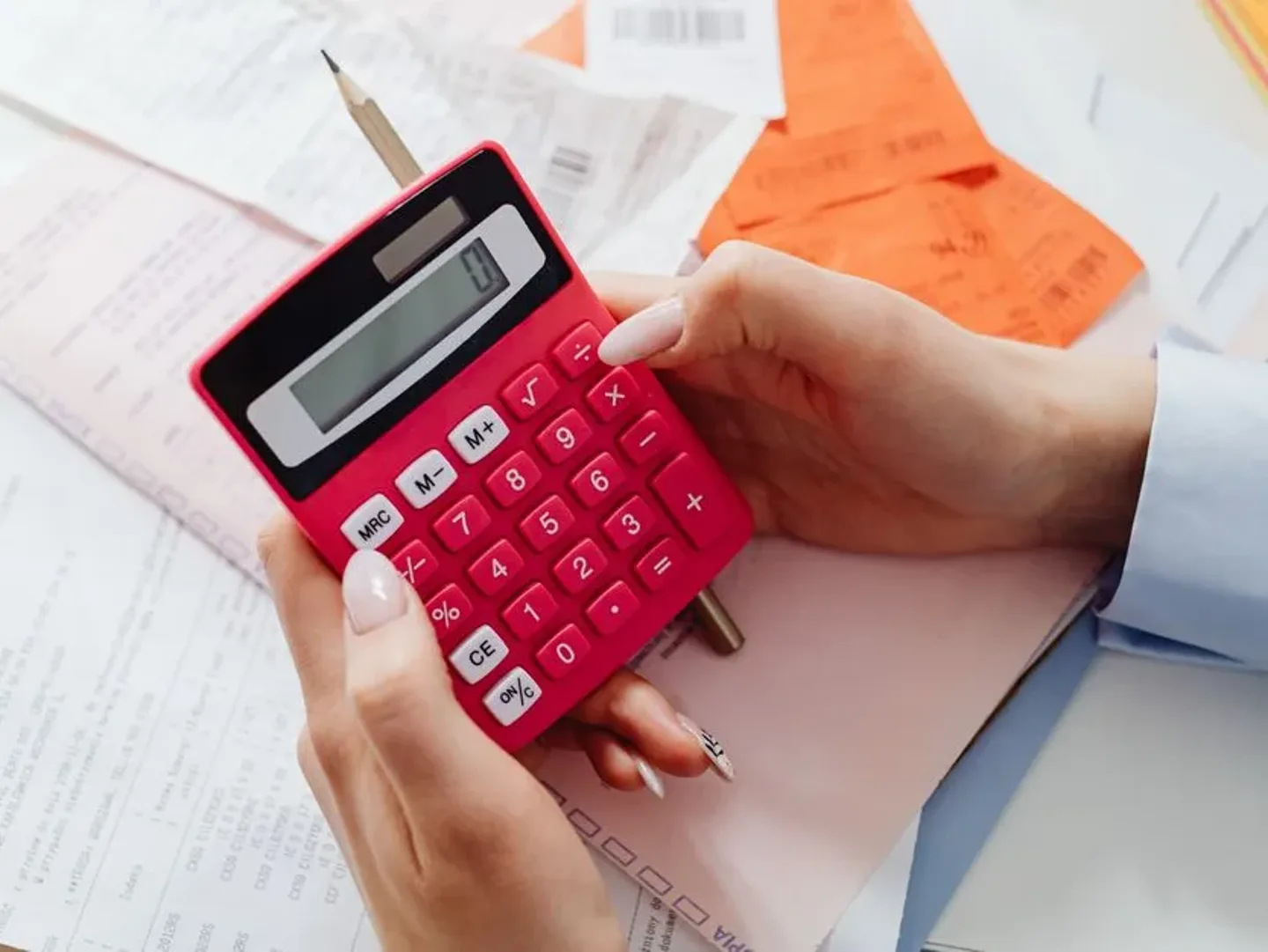 Mains posées sur une calculatrice à côté d’une facture de travaux.